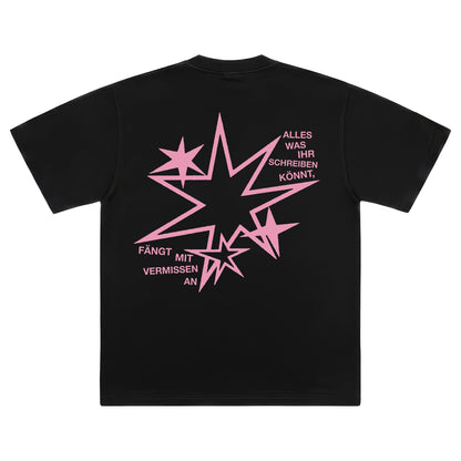 Rückseite eines schwarzen T-Shirts mit einer großen, zackigen rosa Sternengrafik, umrahmt von dem Text „ALLES WAS IHR SCHREIBEN KÖNNT, FÄNGT MIT VERMISSEN AN“.