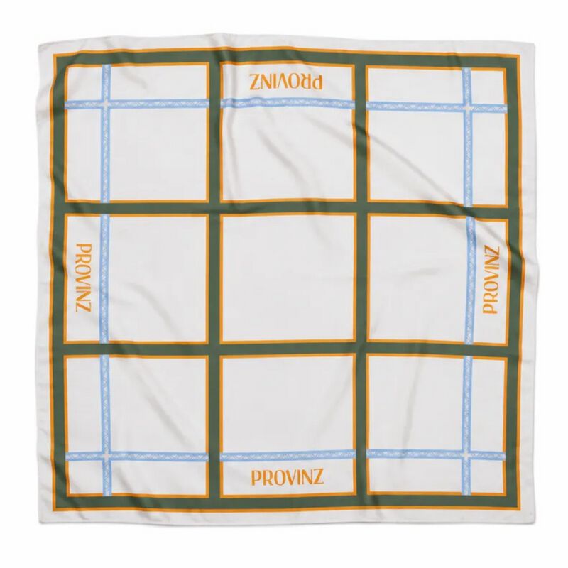 Ein quadratisches Baumwolltuch, das flach ausgebreitet auf weißem Hintergrund liegt. Es zeigt ein geometrisches Muster aus weißen und grünen Rechtecken mit orangen Rändern und dünnen blauen Streifen. In mehreren der weißen Rechtecke ist der Text 'PROVINZ' in orangefarbener Schrift aufgedruckt.